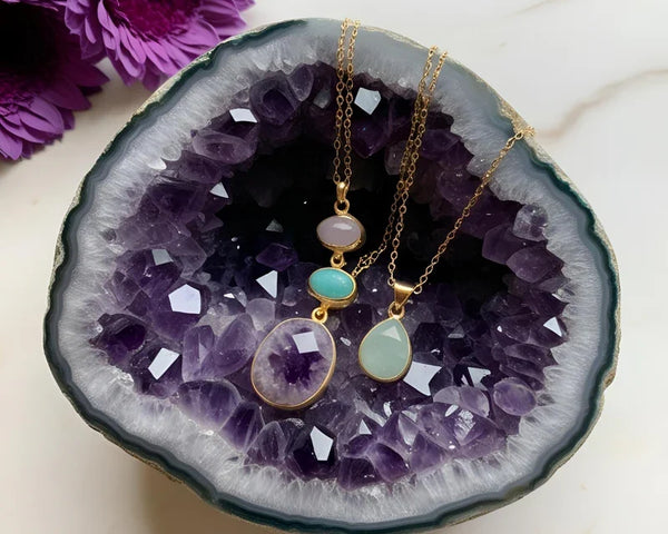 Un assortiment de pierres de lithothérapie (améthyste, quartz rose, etc.) en train d'être recharger par une géode d'améthyste 