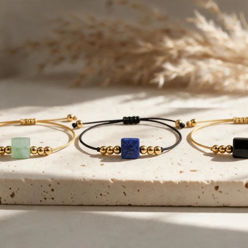 Bracelets cordon doré en pierre naturelle CUBE®, sur travertin