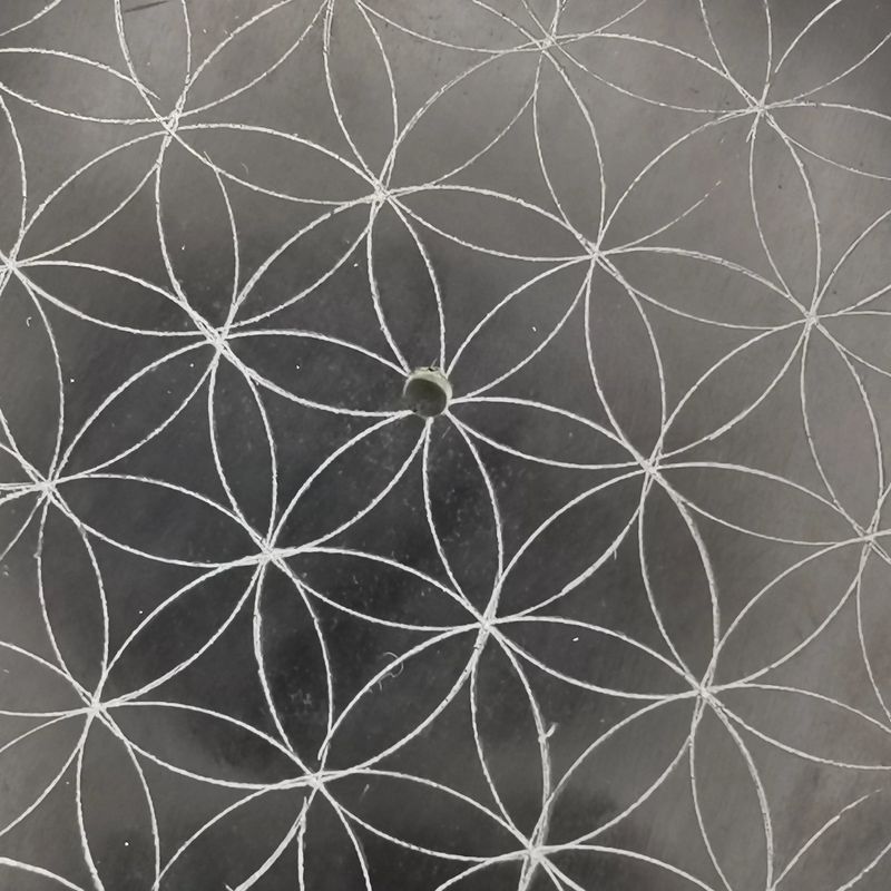 Détail de la gravure Fleur de Vie sur pierre saponite noire ronde, support d'encens naturel