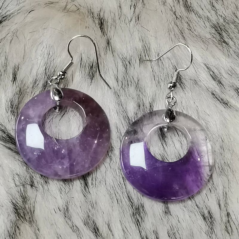 Gros plan sur des boucles d'oreilles en Améthyste véritable, perles rondes violettes, bijou en pierre naturelle