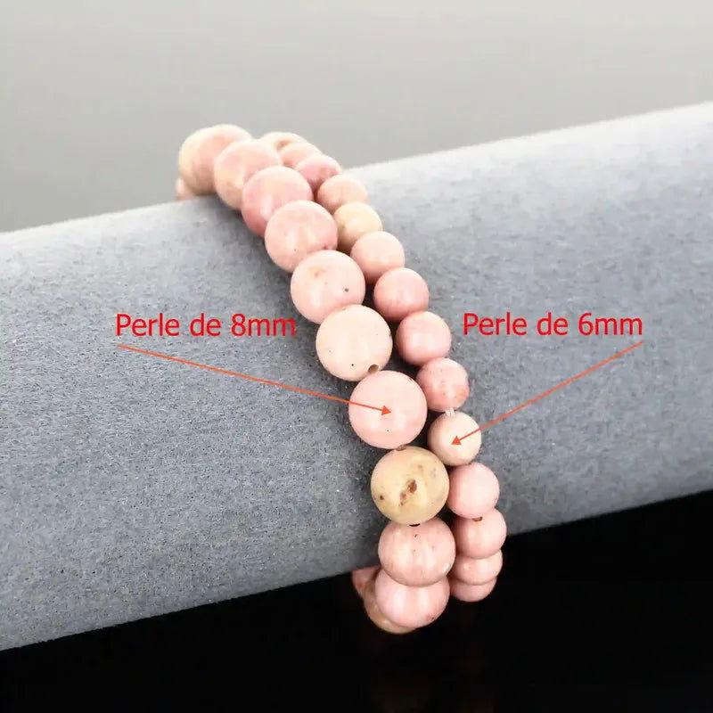 Bracelet de lithothérapie en Rhodonite rose véritable porté au poignet, bijou pierre naturelle pour le pardon et l'équilibre émotionnel.