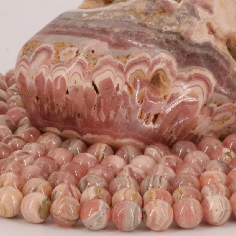 Gros plan sur des perles de Rhodochrosite rose tendre, pierre naturelle ronde et lisse pour bijoux faits main