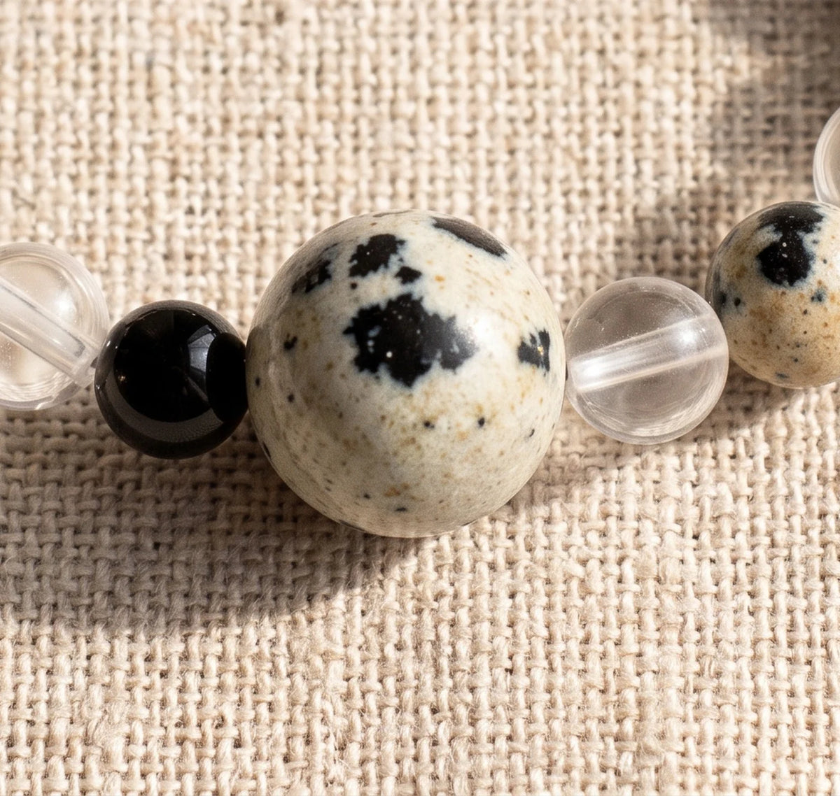 Gros plan sur les perles de jaspe dalmatien de la bague élastique ALÉNA®