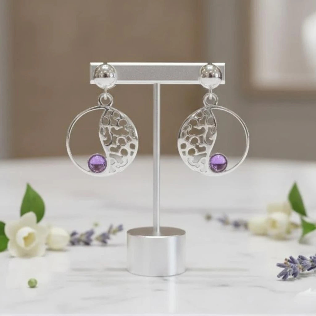 Gros plan sur la pierre et la monture des boucles d'oreilles Bellatrix en améthyste
