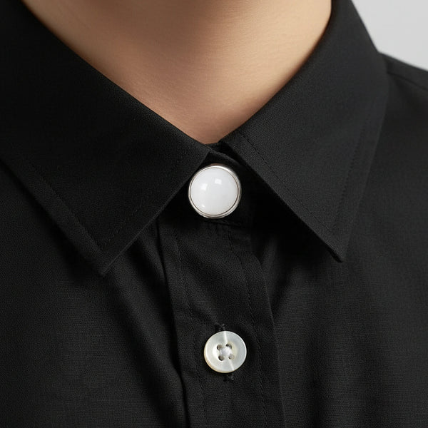 Cache bouton en jade blanc clipsé au col d'une chemise noire