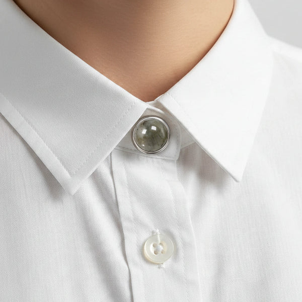 Bijou de chemise en labradorite grise clipsé au col d'une chemise blanche