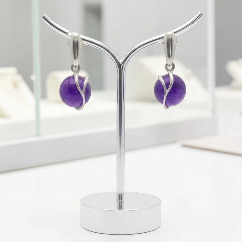 Boucles d'oreilles Aldébaran en améthyste et argent 925 rhodié, présentées sur un support