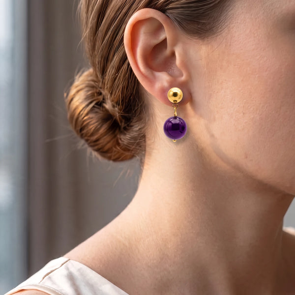 Boucle d'oreille puce dorée et boule d'améthyste violette portée par une femme, idée cadeau