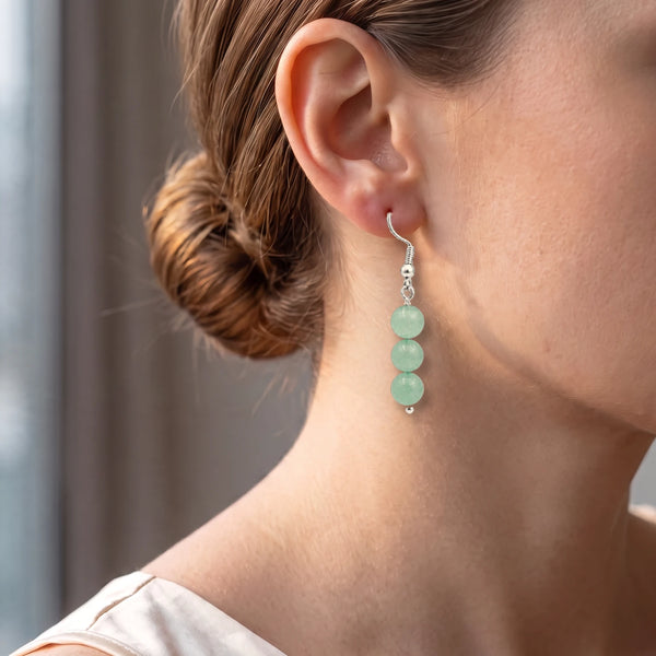 Boucle d'oreille aventurine verte portée à l'oreille d'une femme, bijou pendant aux tons nature