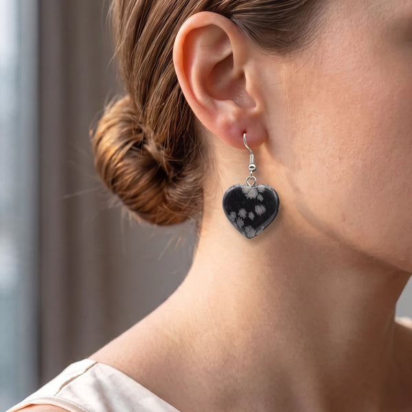 Boucles d'oreilles cœur en obsidienne neige portées par une femme, pendantes sur crochet en acier argenté
