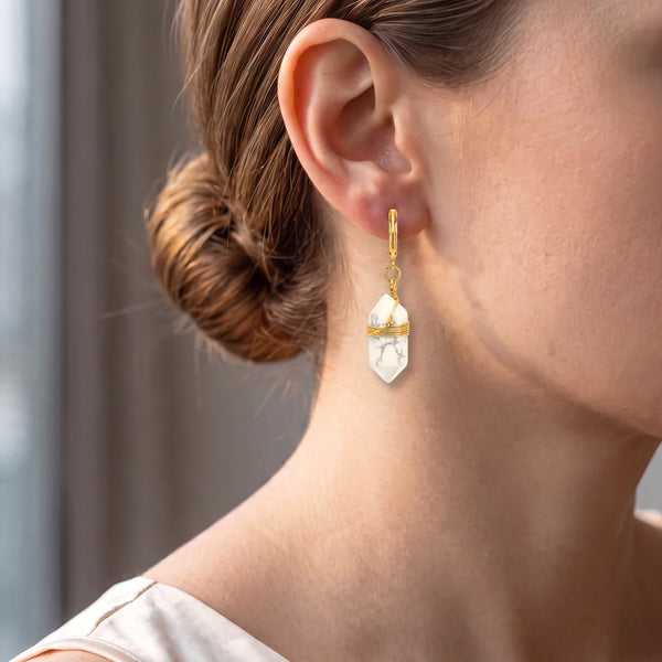 Femme portant une créole dorée à pointe d'howlite blanche, un bijou doux et lumineux