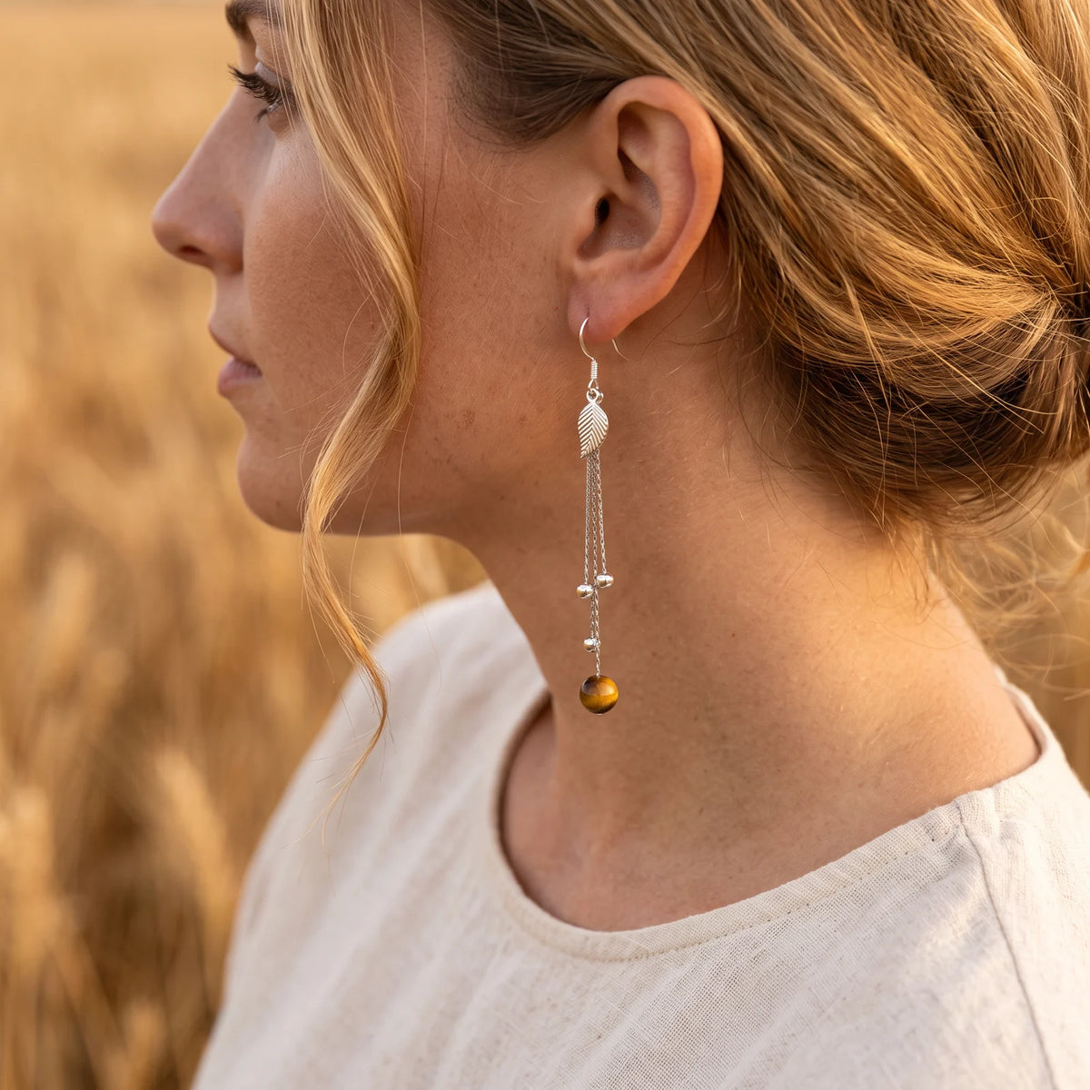 Boucle d'oreille longue en argent massif et œil de tigre, portée à l'oreille