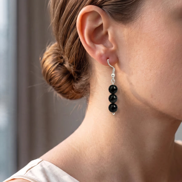 Boucle d'oreille obsidienne noire portée à l'oreille d'une femme, perles boule pour un look chic
