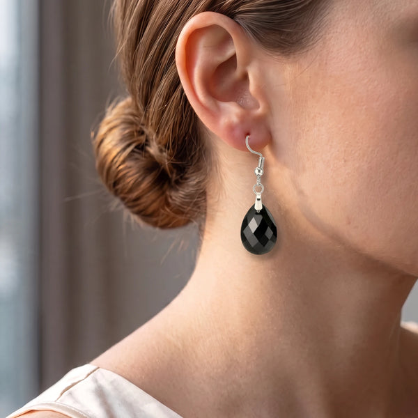 Boucle d'oreille obsidienne noire portée par une femme, goutte facettée brillante pour un look chic