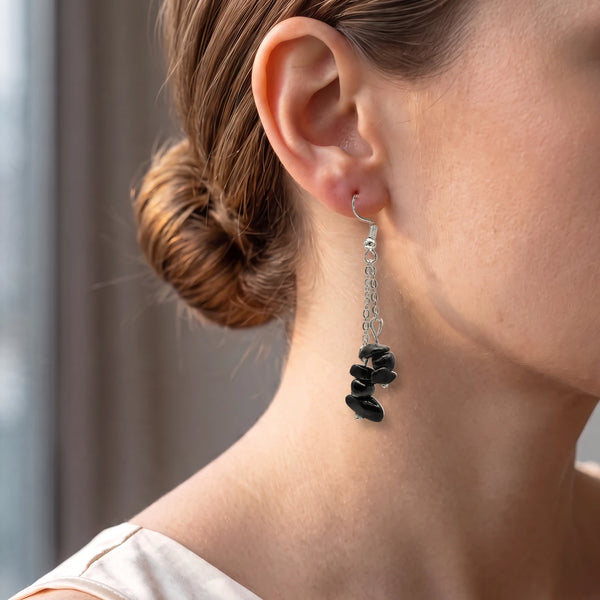 Boucle d'oreille obsidienne noire en chips portée à l'oreille d'une femme, chaîne et crochet argentés