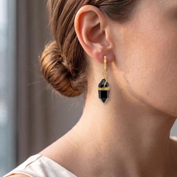 Femme au chignon portant une pointe d'obsidienne noire sur créole dorée, bijou de protection