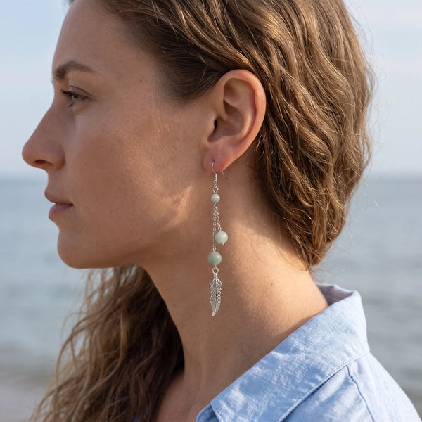 Boucle d'oreille pendante en aigue-marine avec plume argentée, portée à l'oreille