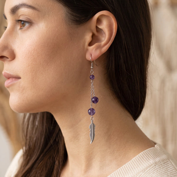 Boucle d'oreille pendante en améthyste avec plume argentée, portée à l'oreille