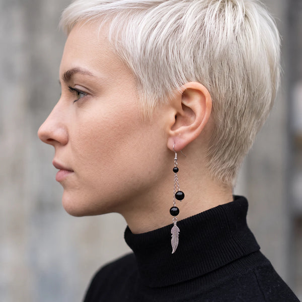 Boucle d'oreille pendante en tourmaline noire avec plume argentée, portée à l'oreille