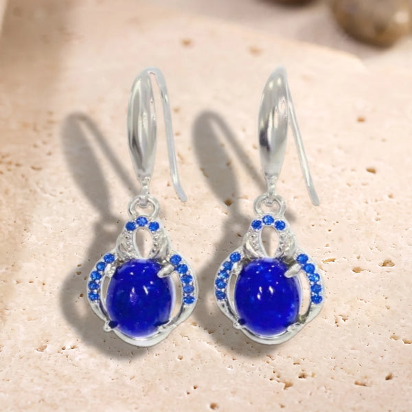 Boucles d'oreilles crochet en argent 925 rhodié, cabochon ovale de lapis-lazuli entouré de petites pierres, sur travertin