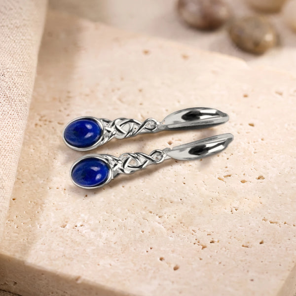 Boucles d'oreilles en lapis-lazuli ovale à motif celtique en argent 925, paire posée sur une dalle de travertin