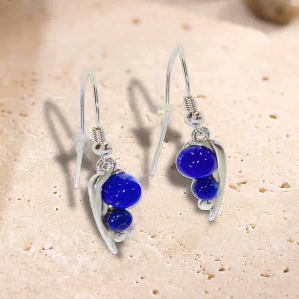 Boucles d'oreilles crochet en argent 925 rhodié, feuille et deux perles de lapis-lazuli, posées à plat sur du travertin