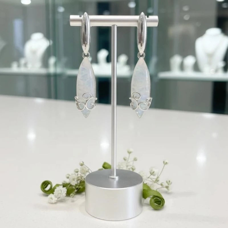 Boucles d'oreilles Mérope en pierre de lune et argent 925 rhodié, présentées sur un support