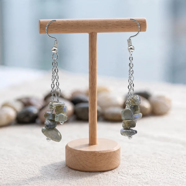Boucles d'oreilles pierre grise à reflets bleus, chips baroques de labradorite sur chaîne argentée, sur un support en bois