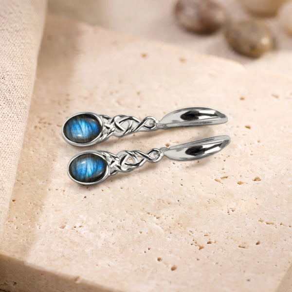 Boucles d'oreilles en labradorite à reflets bleus, cabochon ovale et nœud celtique en argent 925 rhodié, sur travertin