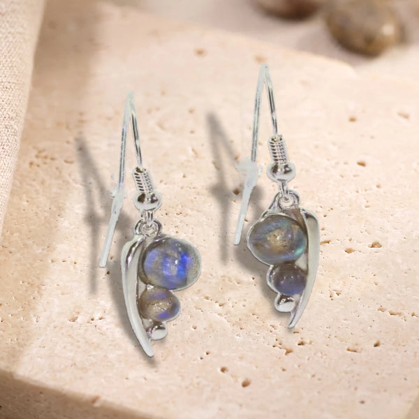 Boucles d'oreilles crochet en argent 925 rhodié, feuille et deux perles de labradorite, posées à plat sur du travertin