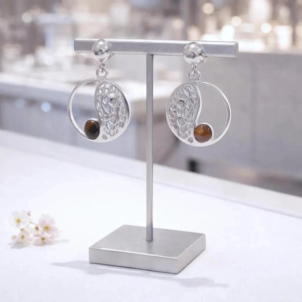 Boucles d'oreilles Dubhe en œil de tigre et argent 925, présentées sur un présentoir à bijoux