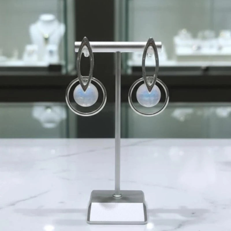 Boucles d'oreilles Céléno en pierre de lune et argent 925, présentées sur un présentoir à bijoux