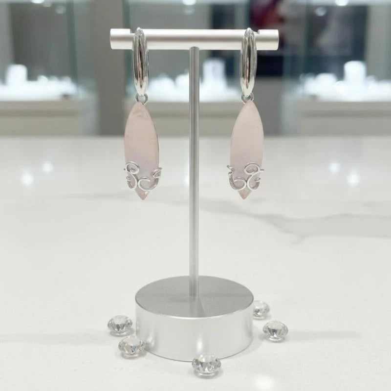 Boucles d'oreilles Alderamin en quartz rose et argent 925, présentées sur un présentoir à bijoux