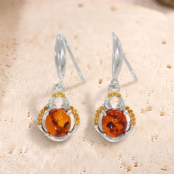 Boucles d'oreilles crochet en argent 925 rhodié, cabochon ovale d'ambre entouré de petites pierres, sur travertin