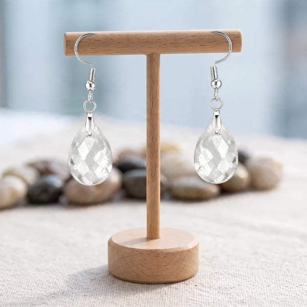 Boucles d'oreilles pierre transparente, goutte de cristal de roche facettée sur crochet argenté, sur un support en bois