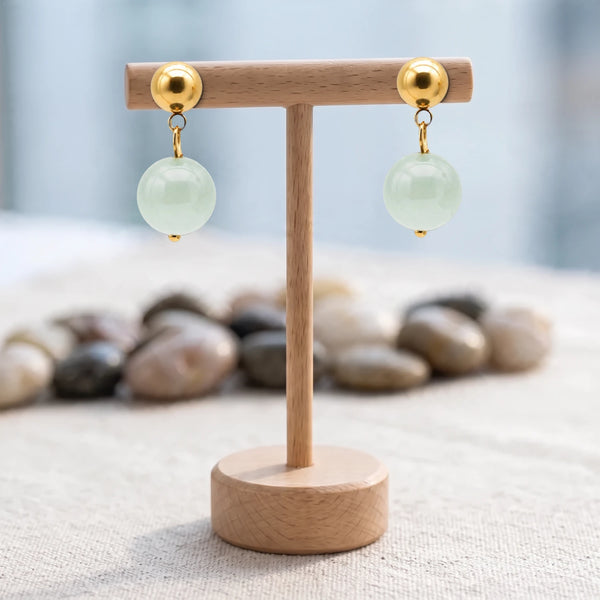 Boucles d'oreilles pierre verte, boule d'aventurine 12 mm sur puce acier doré, présentées sur un support en bois