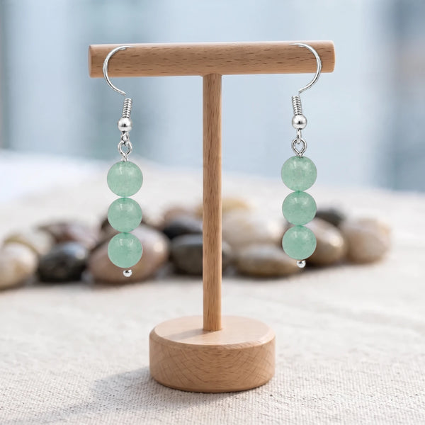 Boucles d'oreilles pierre verte, trois boules d'aventurine sur crochet acier argenté, présentées sur un support en bois