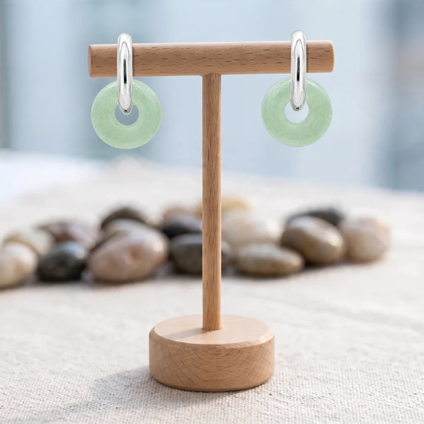 Boucles d'oreilles pierre verte, donut d'aventurine 15 mm sur créole argentée, présentées sur un support en bois