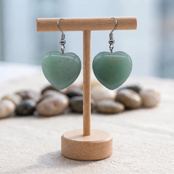 Boucles d'oreilles pierre verte, cœur en aventurine naturelle sur crochet en acier argenté, présentées sur un support en bois