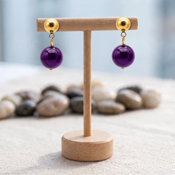 Boucles d'oreilles pierre violette, boule d'améthyste 12 mm sous puce dorée, présentées sur un support en bois