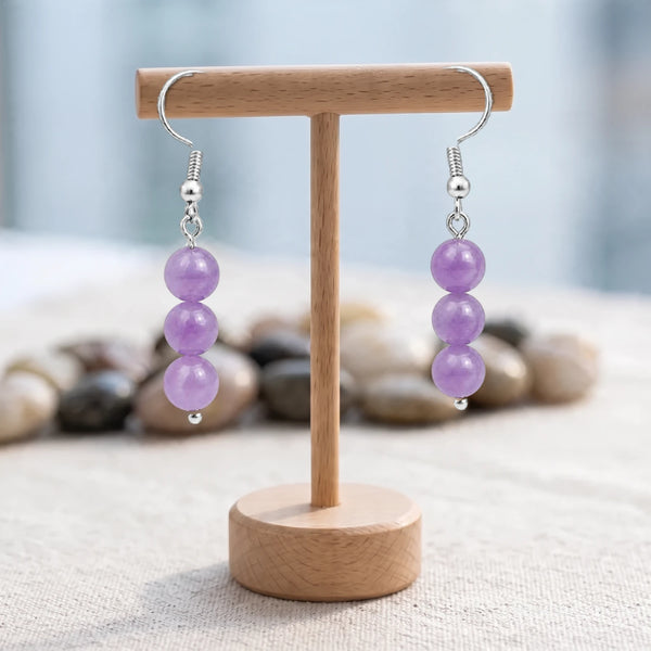 Boucles d'oreilles pierre violette, trois boules d'améthyste de 6 mm sur crochet acier argenté, sur un support en bois