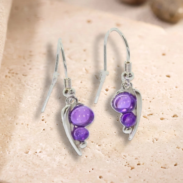 Boucles d'oreilles crochet en argent 925 rhodié, feuille et deux perles d'améthyste, posées à plat sur du travertin