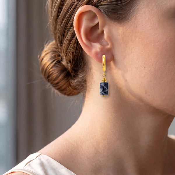 Créole dorée avec tube de sodalite bleu nuit portée à l'oreille d'une femme, bijou chic