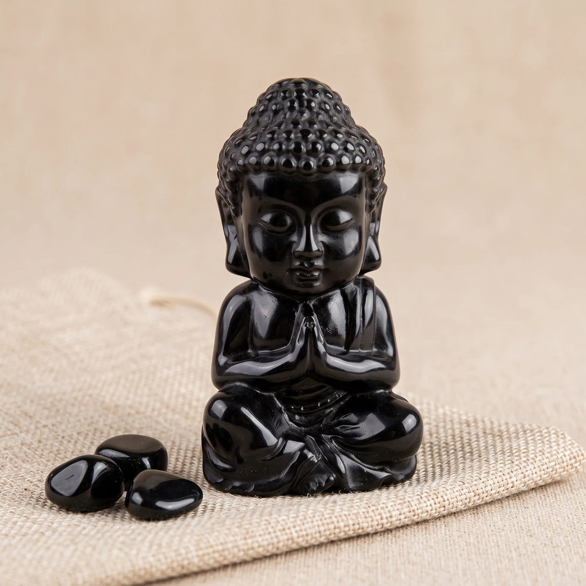 Bouddha en pierre obsidienne noire taillé dans la masse, avec des pierres roulées