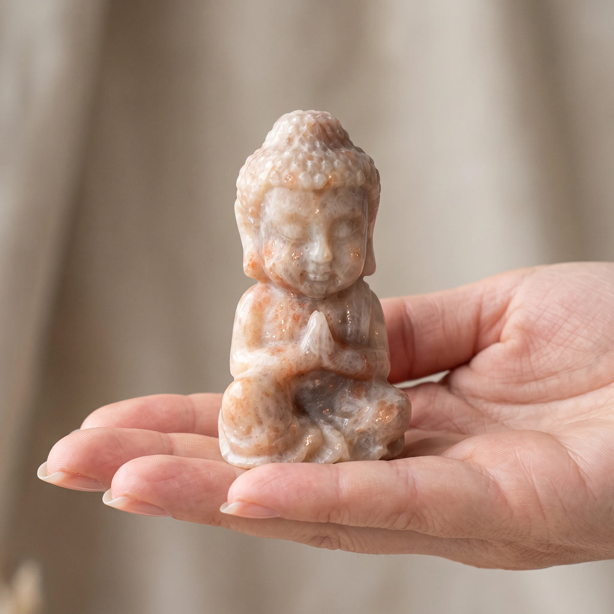 Bouddha miniature en pierre de soleil taillé artisanalement, tenu dans la main