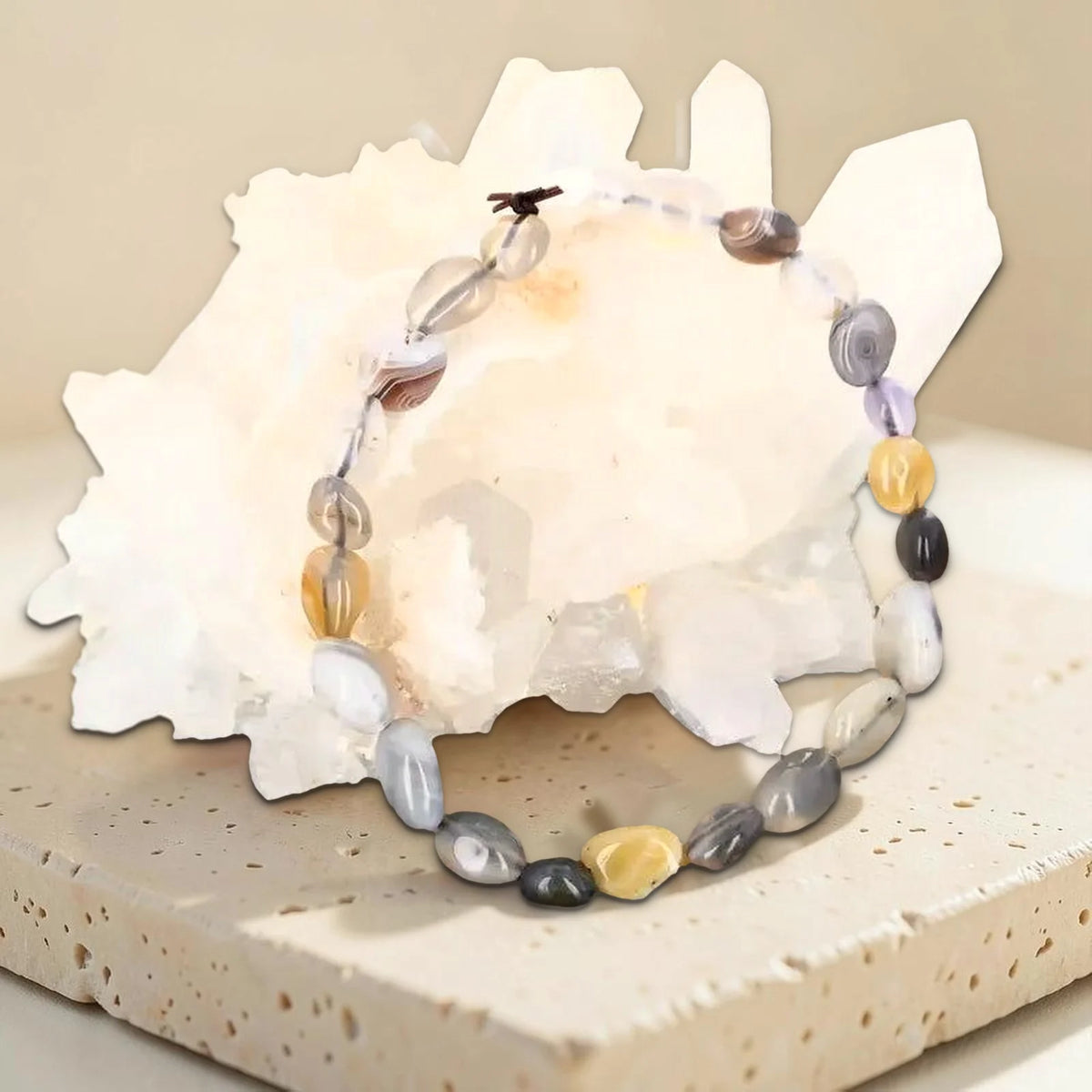Bracelet pierre roulée agate rubanée, photo réelle sur travertin contre un amas de cristal