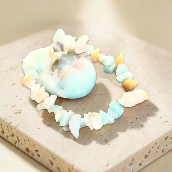 Bracelet en pépites d'amazonite et sa pierre roulée d'amazonite posés sur du travertin, bijou zen bleu vert