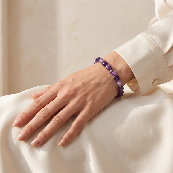 Bracelet anti-stress en améthyste roulée porté au poignet d'une femme, bijou violet en pierre naturelle