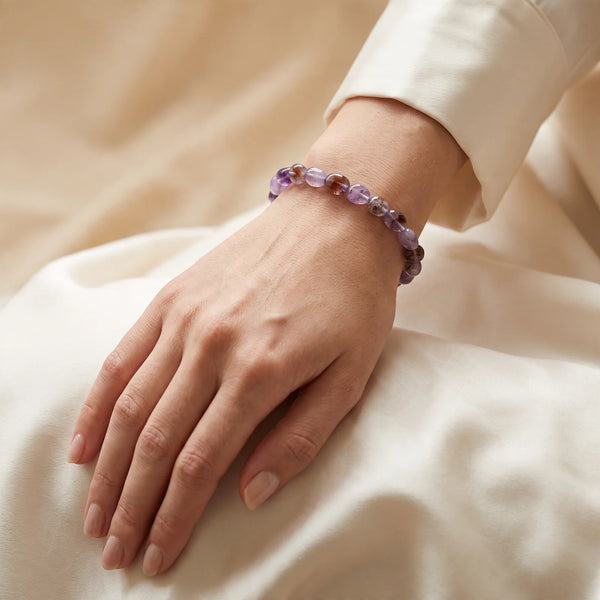 Bracelet auralite 23 porté par une femme, pierres roulées violet et prune au poignet