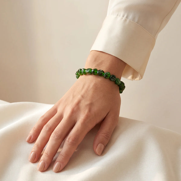 Bracelet diopside porté au poignet d'une femme, pierres roulées d'un vert profond